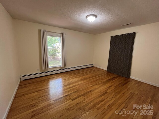 511 Evelyn Ave, Kannapolis, NC 28083 - unfurnished room featuring a baseboard heating unit, wood finished floors, a textured ceiling, and baseboards