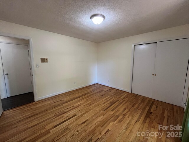 511 Evelyn Ave, Kannapolis, NC 28083 - unfurnished bedroom with wood finished floors, a textured ceiling, a closet, and baseboards