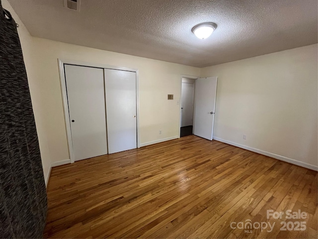 511 Evelyn Ave, Kannapolis, NC 28083 - unfurnished bedroom featuring wood finished floors, a textured ceiling, a closet, and baseboards