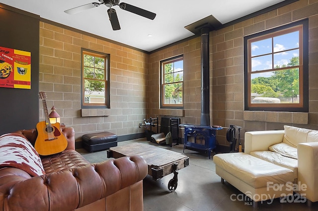 14701 Cabarrus Rd, Mint Hill, NC 28227 - living area featuring a wood stove, finished concrete flooring, ceiling fan, and concrete block wall