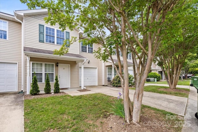 view of property featuring concrete driveway, an attached garage, and a front lawn