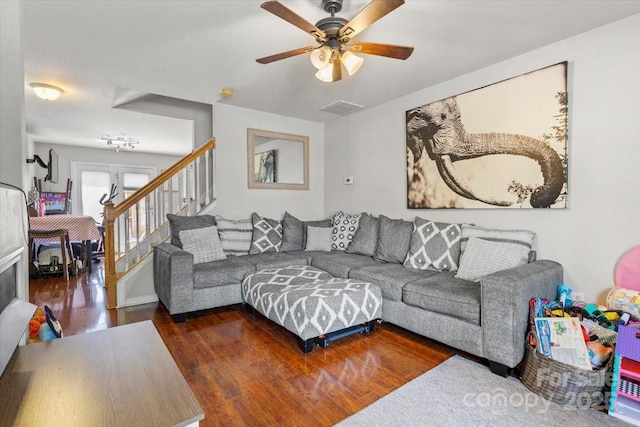living area featuring wood finished floors, a ceiling fan, and stairway