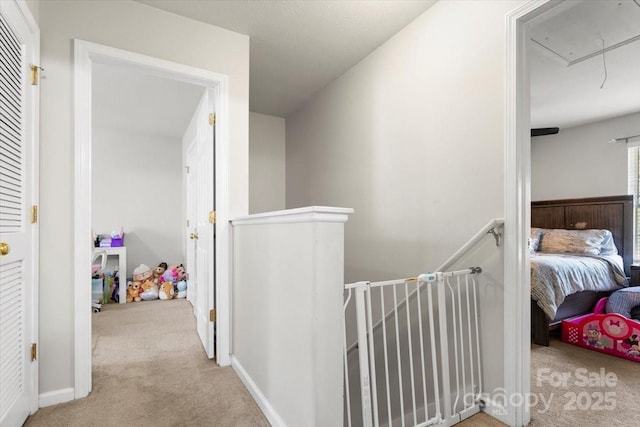 hall with an upstairs landing, carpet, and attic access