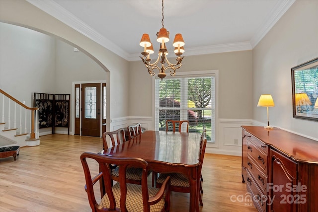 3124 17th Street Ln NE, Hickory, NC 28601 - dining space featuring a chandelier, arched walkways, light wood finished floors, wainscoting, and stairs