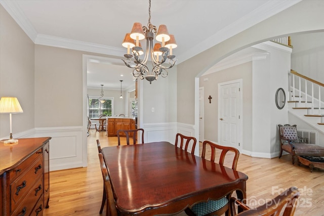 3124 17th Street Ln NE, Hickory, NC 28601 - dining room with arched walkways, light wood-type flooring, a chandelier, stairs, and wainscoting