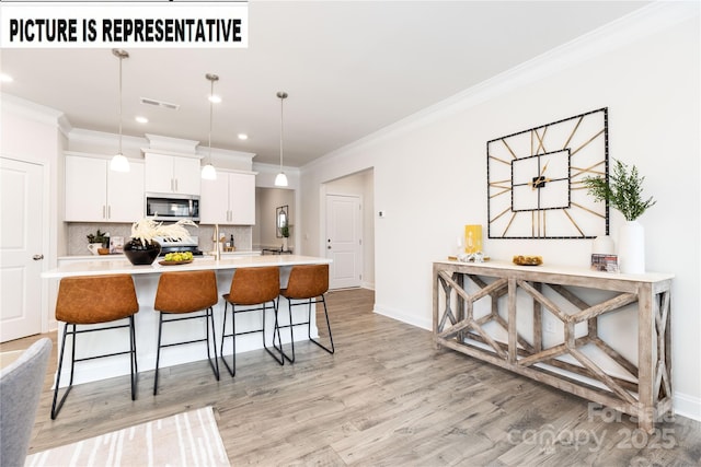 121 S Shayna Rd, Troutman, NC 28166 - kitchen with appliances with stainless steel finishes, light wood-style flooring, a breakfast bar area, light countertops, and a kitchen island with sink
