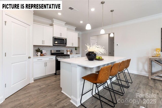 121 S Shayna Rd, Troutman, NC 28166 - kitchen featuring stainless steel appliances, crown molding, a center island, white cabinetry, and backsplash