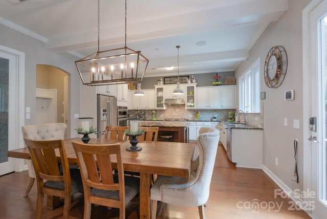 3666 Jacinta Ct, Tega Cay, SC 29708 - dining area featuring wood finished floors, arched walkways, crown molding, beam ceiling, and baseboards