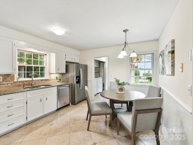 1049 Regency Dr, Charlotte, NC 28211 - kitchen featuring stainless steel appliances, a sink, washing machine and dryer, a chandelier, and backsplash