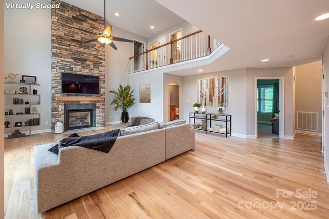 206 Ridge Top Dr, Connelly Springs, NC 28612 - living area with ceiling fan, light wood-style flooring, arched walkways, a fireplace, and a towering ceiling