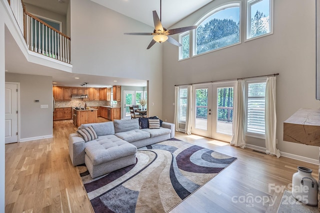 206 Ridge Top Dr, Connelly Springs, NC 28612 - living room featuring light wood-style floors, french doors, a ceiling fan, a towering ceiling, and baseboards