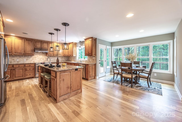 206 Ridge Top Dr, Connelly Springs, NC 28612 - kitchen featuring under cabinet range hood, brown cabinetry, a sink, stainless steel appliances, and light wood-style floors