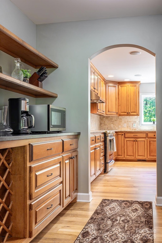 206 Ridge Top Dr, Connelly Springs, NC 28612 - kitchen with arched walkways, light wood-style flooring, appliances with stainless steel finishes, tasteful backsplash, and under cabinet range hood