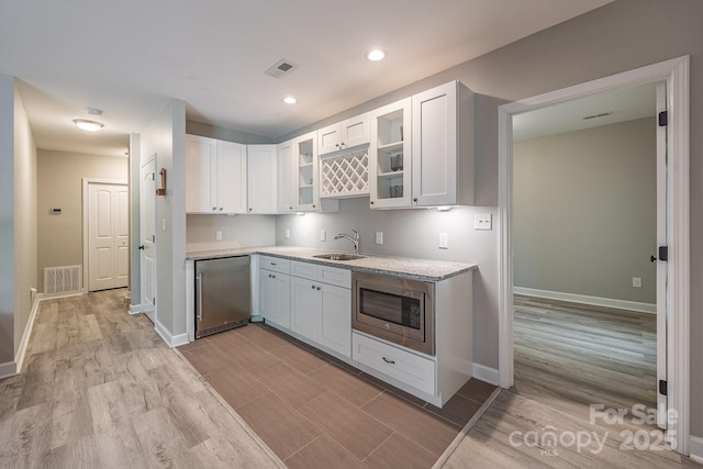 206 Ridge Top Dr, Connelly Springs, NC 28612 - kitchen with stainless steel microwave, a sink, light wood-style flooring, white cabinetry, and light countertops