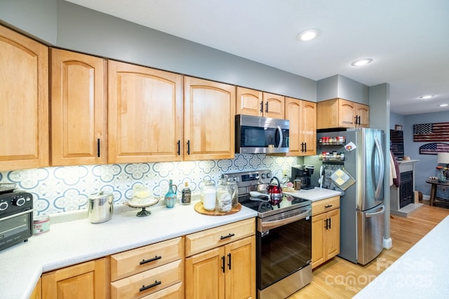 kitchen with appliances with stainless steel finishes, light countertops, light wood-style floors, light brown cabinetry, and recessed lighting