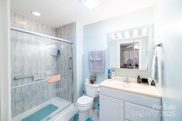 full bathroom featuring toilet, a shower stall, vanity, and a textured ceiling