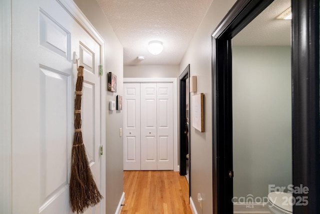 hallway featuring light wood-style flooring and a textured ceiling