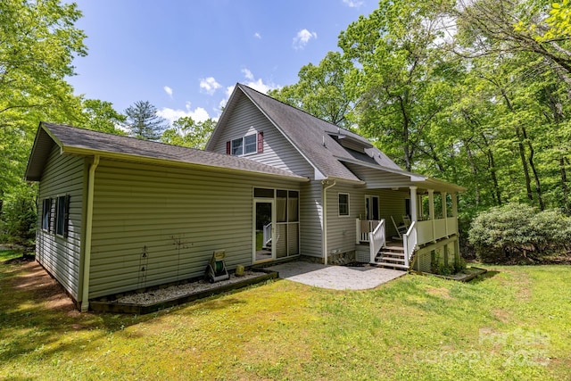 rear view of house featuring a yard, roof with shingles, and covered porch