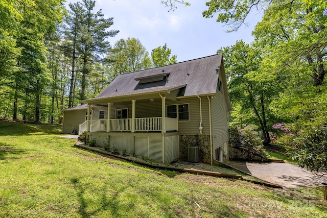 back of property featuring cooling unit, a lawn, a porch, a shingled roof, and stone siding