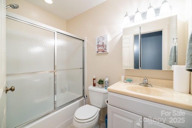 bathroom with vanity, toilet, and bath / shower combo with glass door