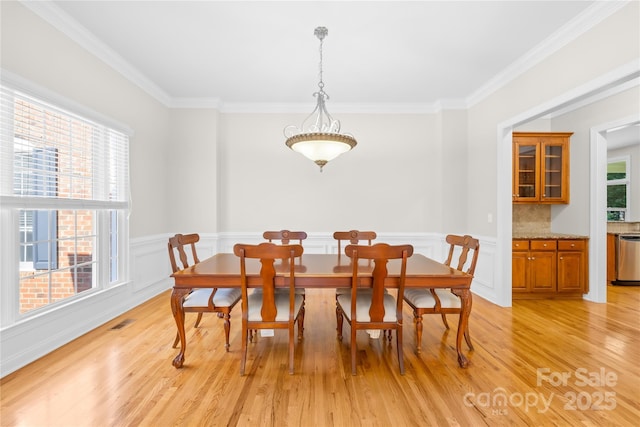 10024 Hazelview Dr, Charlotte, NC 28277 - dining space with ornamental molding, light wood finished floors, and a wainscoted wall