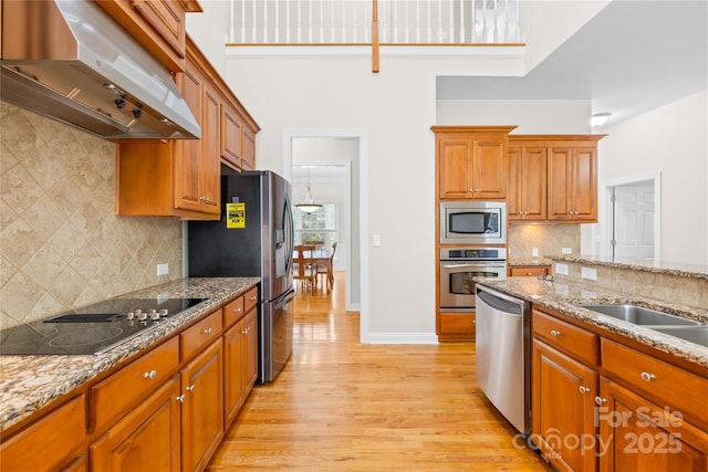 10024 Hazelview Dr, Charlotte, NC 28277 - kitchen featuring appliances with stainless steel finishes, range hood, light wood-type flooring, decorative backsplash, and brown cabinetry