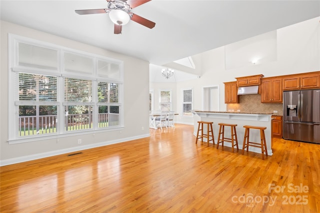 10024 Hazelview Dr, Charlotte, NC 28277 - kitchen with stainless steel fridge with ice dispenser, a breakfast bar area, a chandelier, light wood-style floors, and under cabinet range hood