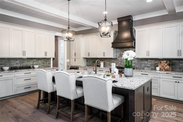 7703 Juniper Ln, Denver, NC 28037 - kitchen with custom exhaust hood, beam ceiling, tasteful backsplash, a breakfast bar area, and an island with sink