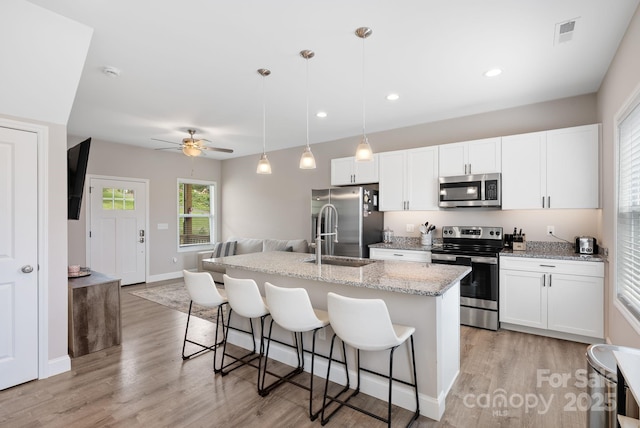 2242 Bear Creek Rd, Leicester, NC 28748 - kitchen featuring appliances with stainless steel finishes, a kitchen bar, a sink, a kitchen island with sink, and light wood-style flooring
