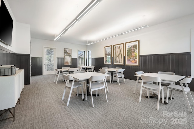 dining room featuring a wainscoted wall and light carpet