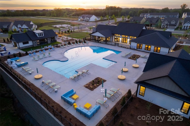 community pool with fence, a residential view, and a patio area