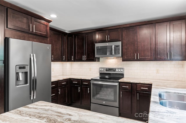 82 Sunburst Dr, Waynesville, NC 28786 - kitchen featuring stainless steel appliances, light stone counters, dark brown cabinetry, backsplash, and a sink