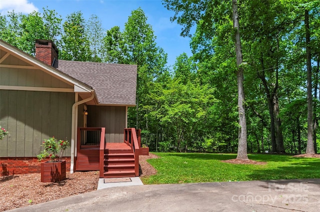 82 Sunburst Dr, Waynesville, NC 28786 - view of exterior entry featuring a shingled roof, a chimney, a lawn, and a wooden deck