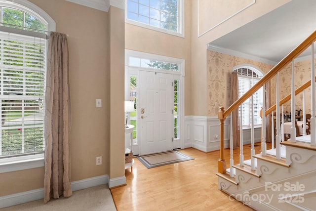 4389 Enchantment Cove Ln, Charlotte, NC 28216 - entrance foyer with ornamental molding, wallpapered walls, wainscoting, stairway, and wood finished floors