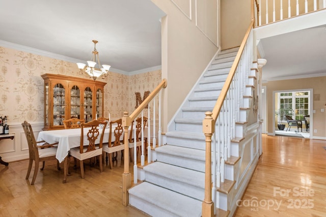 4389 Enchantment Cove Ln, Charlotte, NC 28216 - stairway with wallpapered walls, wood finished floors, a chandelier, crown molding, and wainscoting