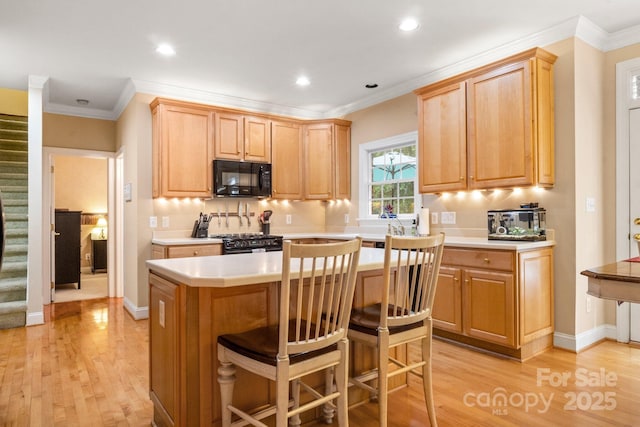 4389 Enchantment Cove Ln, Charlotte, NC 28216 - kitchen featuring black appliances, light wood-style floors, light countertops, a kitchen island, and a kitchen breakfast bar