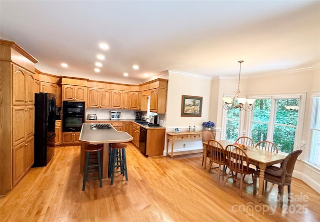 10317 Clubhouse View Ln, Mint Hill, NC 28227 - kitchen with black appliances, light wood-style floors, a chandelier, a kitchen island, and a kitchen breakfast bar