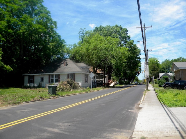 view of asphalt road featuring street lighting, curbs, and traffic signs