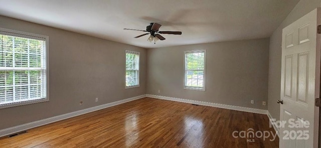 unfurnished room featuring healthy amount of natural light, baseboards, and wood finished floors