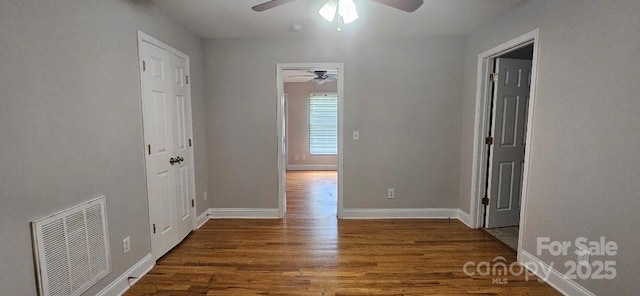 unfurnished room with ceiling fan, wood finished floors, and baseboards