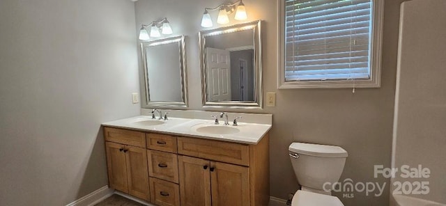full bathroom featuring toilet, double vanity, and baseboards