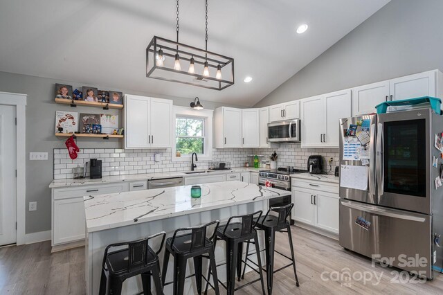 1138 Zeb Haynes Rd, Maiden, NC 28650 - kitchen featuring stainless steel appliances, vaulted ceiling, decorative backsplash, white cabinetry, and a kitchen breakfast bar