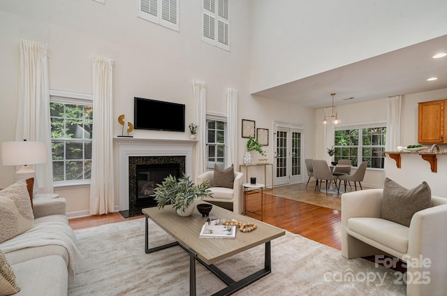 2504 Korbel Ct, Waxhaw, NC 28173 - living room with light wood-style flooring, a high end fireplace, a chandelier, a towering ceiling, and recessed lighting