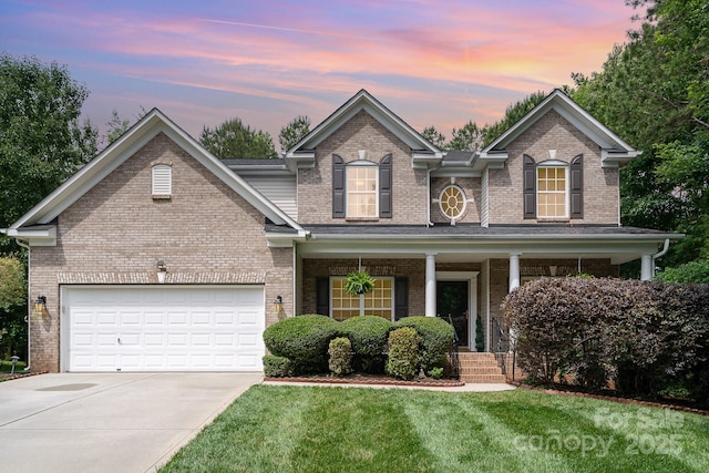 2504 Korbel Ct, Waxhaw, NC 28173 - traditional home with brick siding, driveway, covered porch, a lawn, and a garage