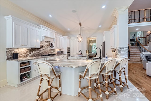 1056 James Madison Dr, Matthews, NC 28104 - kitchen featuring a peninsula, light stone countertops, gas stovetop, white cabinets, and decorative backsplash