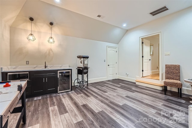 1056 James Madison Dr, Matthews, NC 28104 - kitchen with beverage cooler, lofted ceiling, dark cabinetry, wood finished floors, and a sink