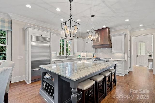 18718 Peninsula Cove Ln, Cornelius, NC 28031 - kitchen featuring built in fridge, custom exhaust hood, a sink, ornamental molding, and a center island