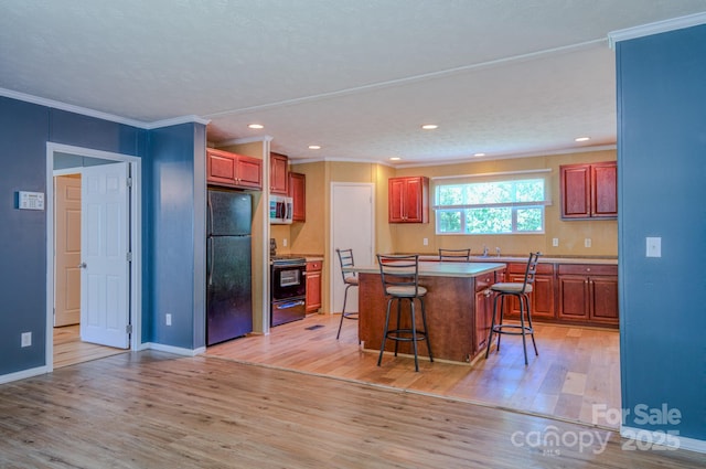 4065 NC-126 Hwy, Morganton, NC 28655 - kitchen featuring black appliances, light wood finished floors, a kitchen bar, a kitchen island, and ornamental molding