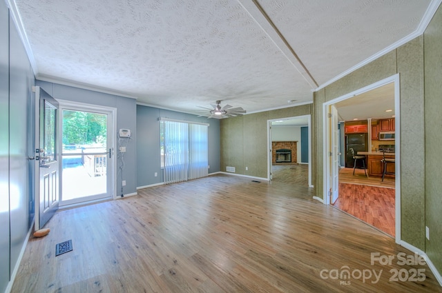 4065 NC-126 Hwy, Morganton, NC 28655 - unfurnished living room with crown molding, wood finished floors, ceiling fan, a textured ceiling, and a fireplace