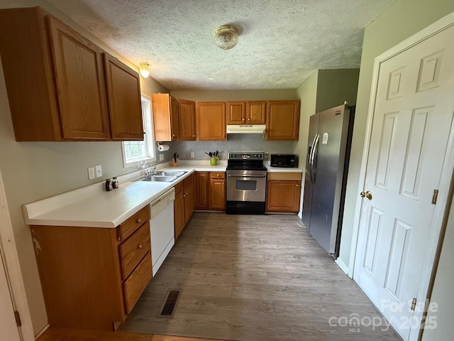 405 Jose St, Shelby, NC 28150 - kitchen with appliances with stainless steel finishes, under cabinet range hood, a sink, brown cabinetry, and a textured ceiling